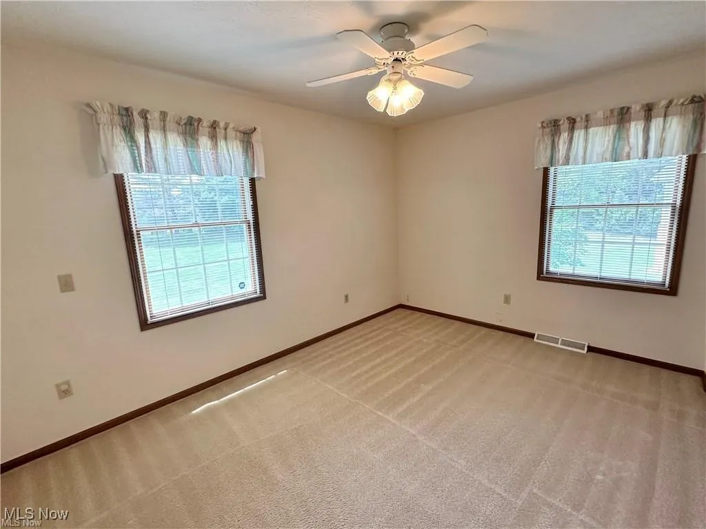 Unfurnished room featuring light colored carpet and a ceiling fan