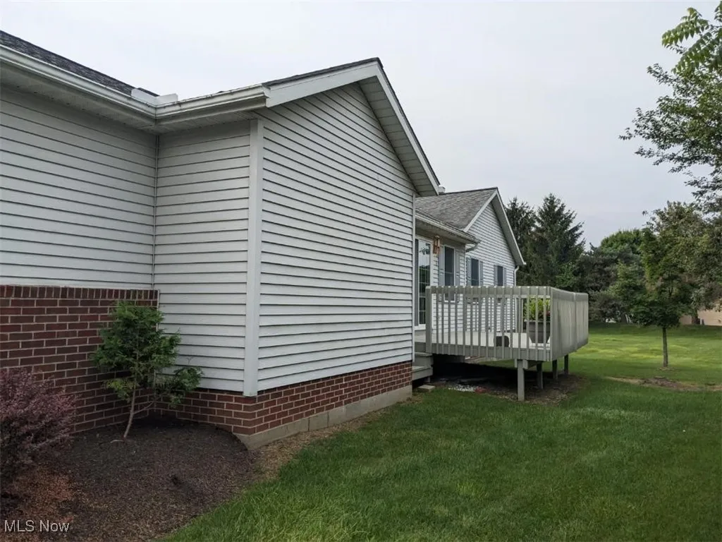 View of home's exterior featuring a wooden deck and a lawn