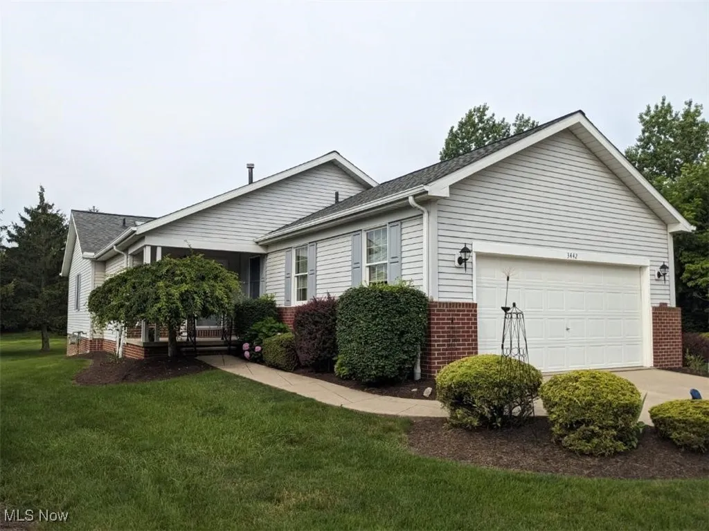 View of property exterior featuring an attached garage, brick siding, a yard, and concrete driveway