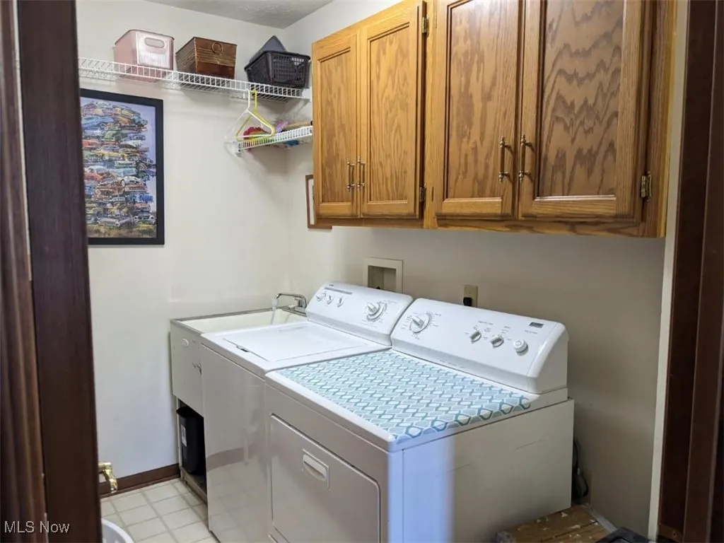 Laundry room with independent washer and dryer, cabinet space, and light flooring