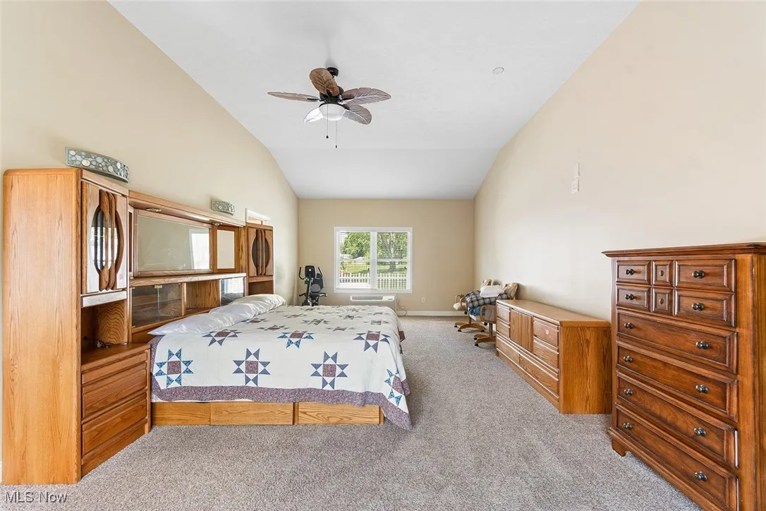 Bedroom with vaulted ceiling, carpet floors, and a ceiling fan
