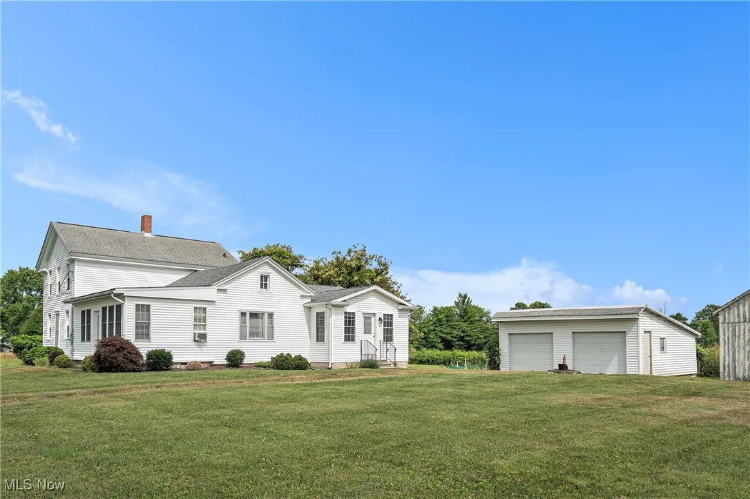 View of front of house featuring a detached garage, a front lawn, and a chimney