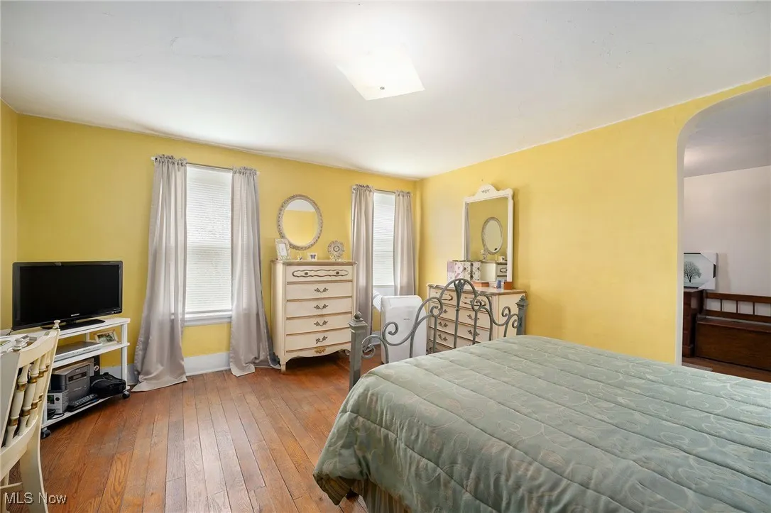 Bedroom featuring multiple windows, arched walkways, and wood-type flooring