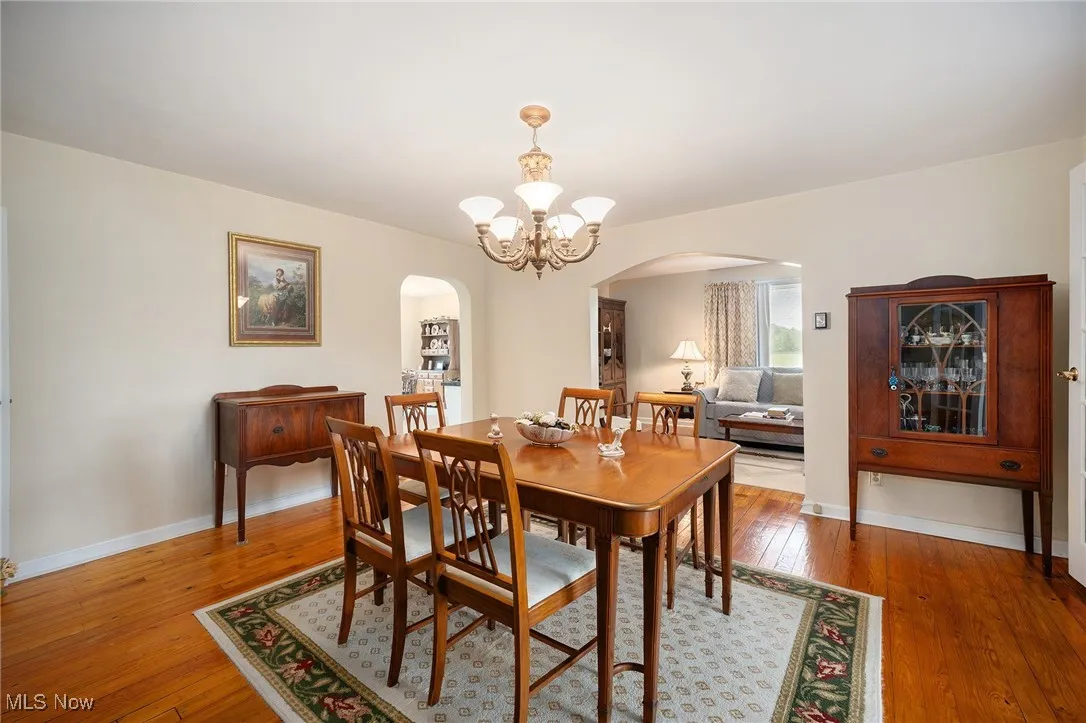 Dining area with arched walkways, a chandelier, and hardwood / wood-style flooring