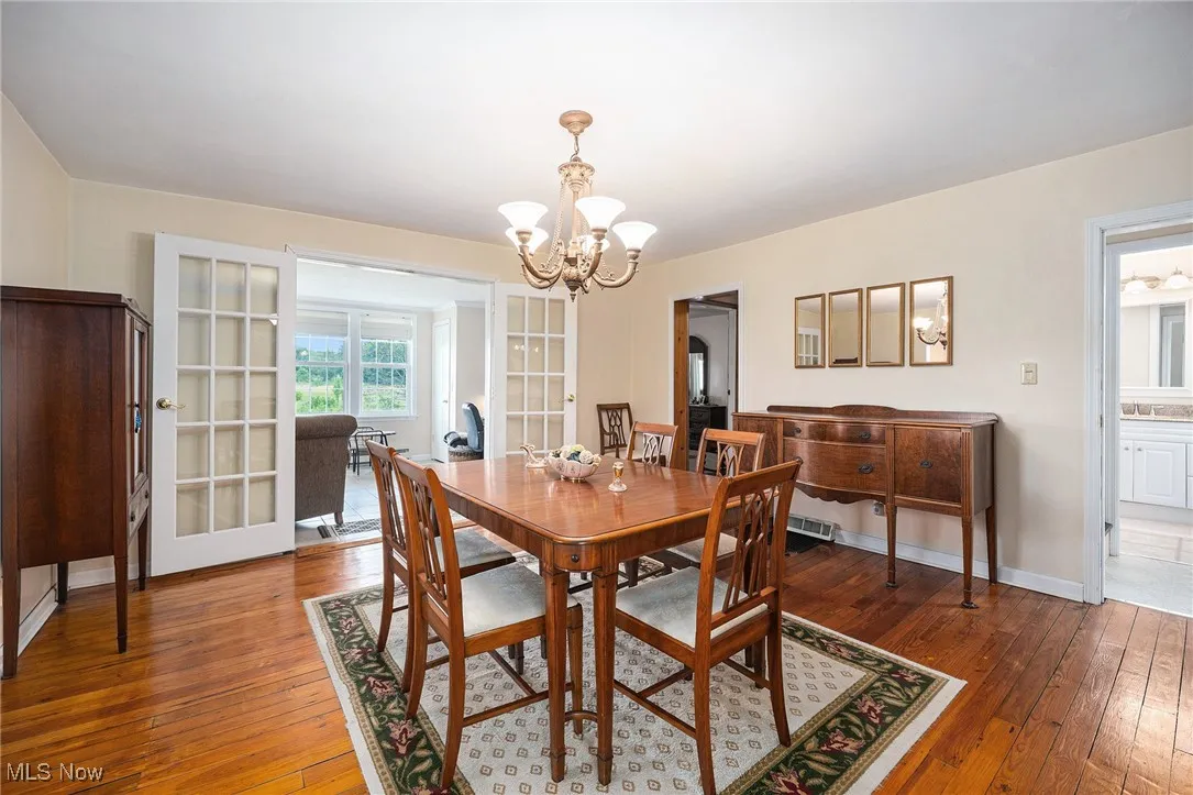 Dining room with hardwood / wood-style flooring, a chandelier, french doors, and arched walkways