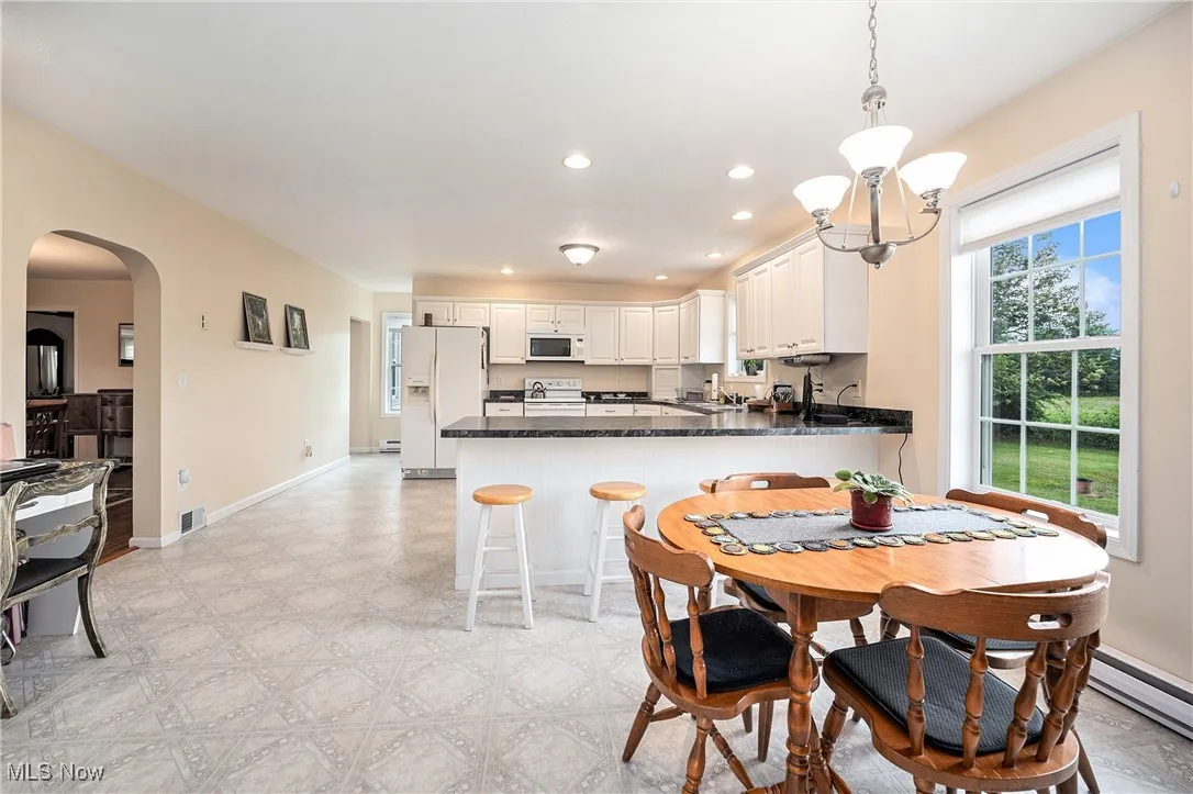 Dining space with arched walkways, light flooring, and recessed lighting