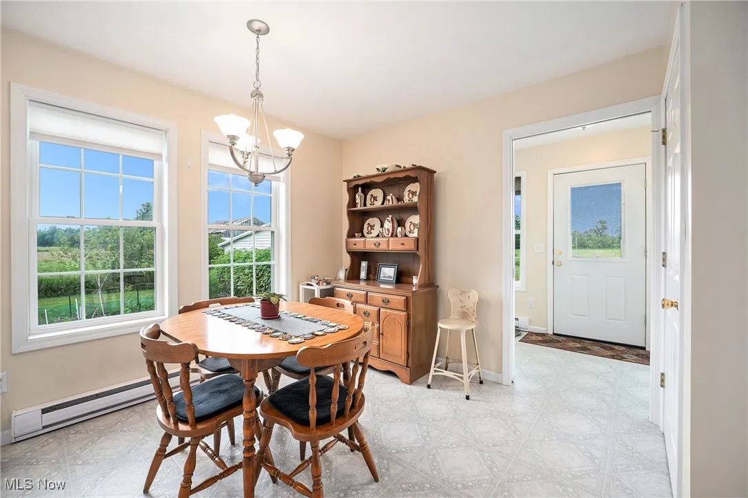 Dining area featuring a baseboard radiator, light flooring, and a chandelier