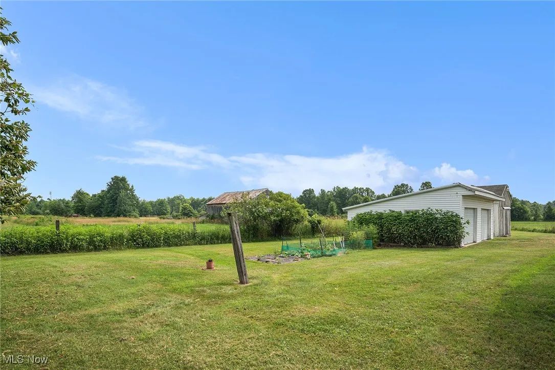 View of grassy yard featuring a detached garage and an outdoor structure
