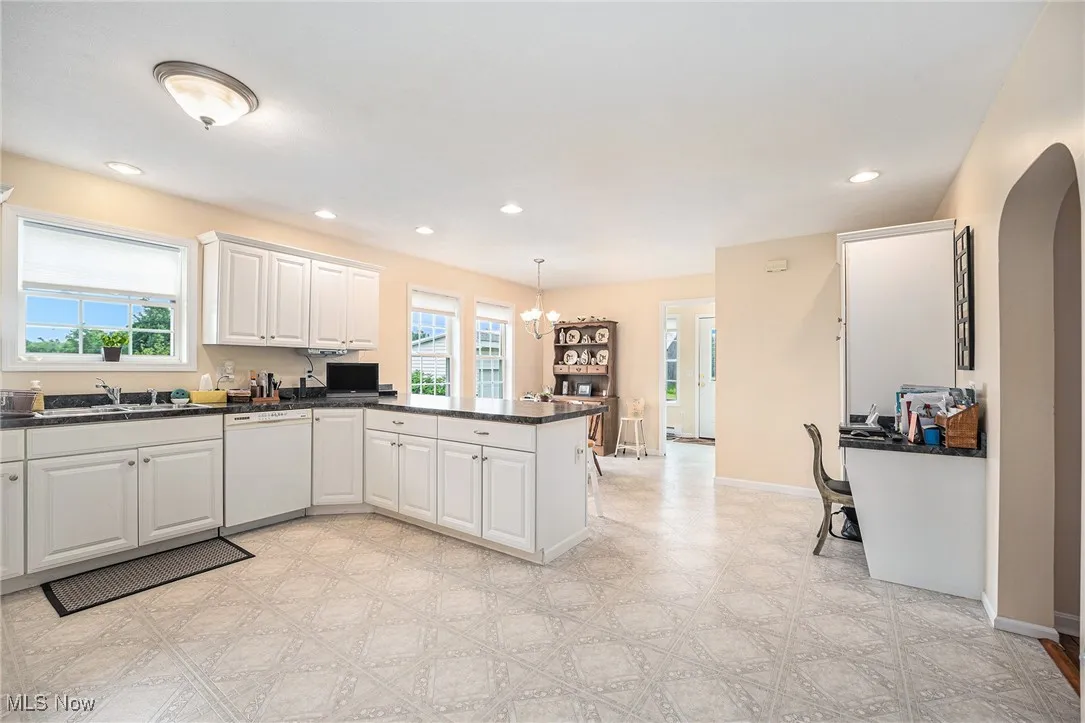 Kitchen featuring dishwasher, a peninsula, plenty of natural light, dark countertops, and recessed lighting