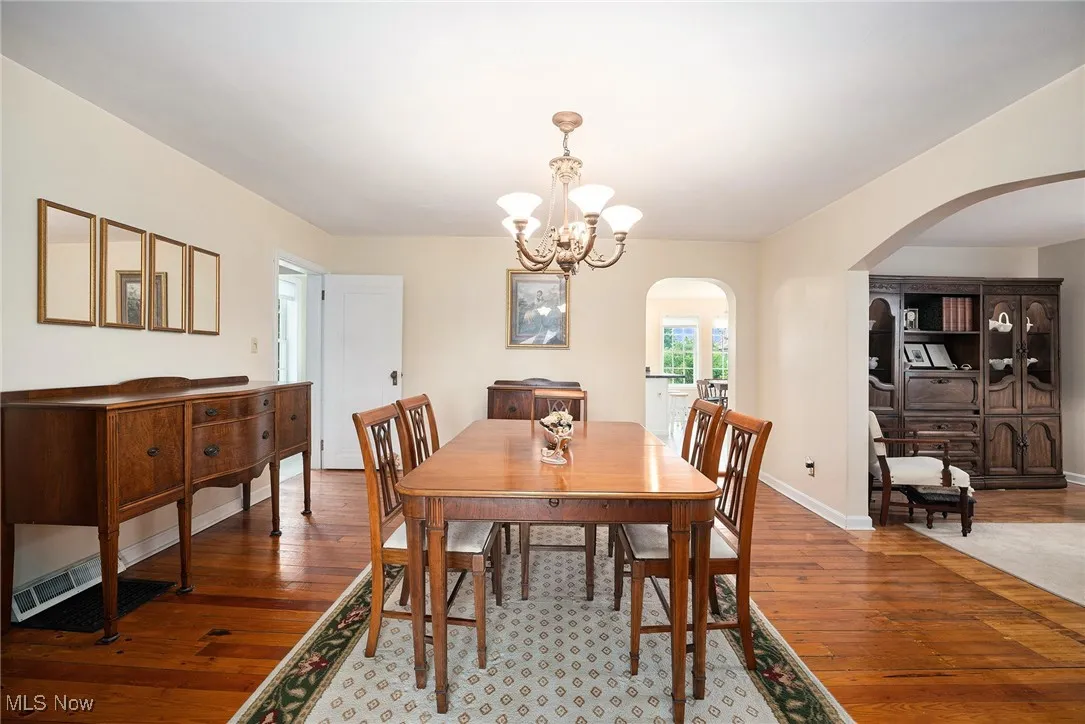 Dining room with arched walkways, a chandelier, and hardwood / wood-style flooring