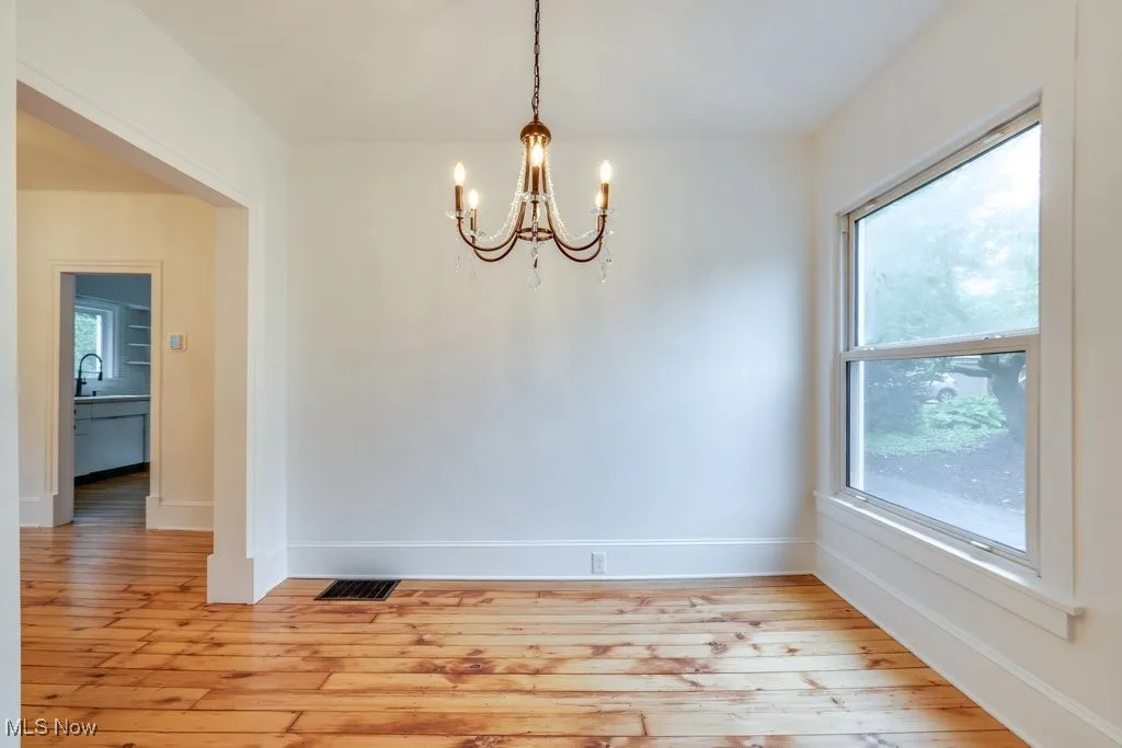 Unfurnished dining area with a chandelier, light wood-style floors, and plenty of natural light