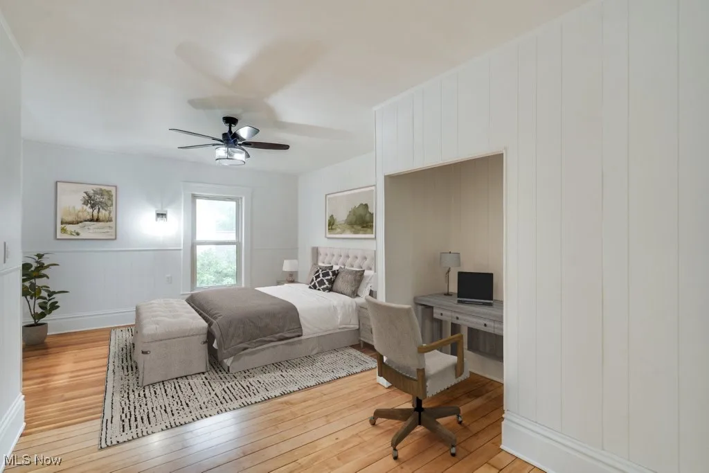Bedroom with light wood finished floors, a decorative wall, and a ceiling fan