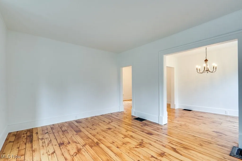 Spare room with a chandelier and light wood finished floors