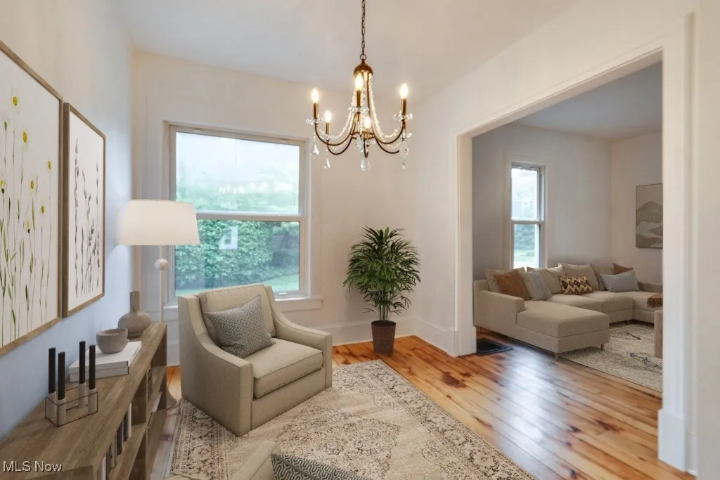 Sitting room featuring healthy amount of natural light, wood-type flooring, and a chandelier