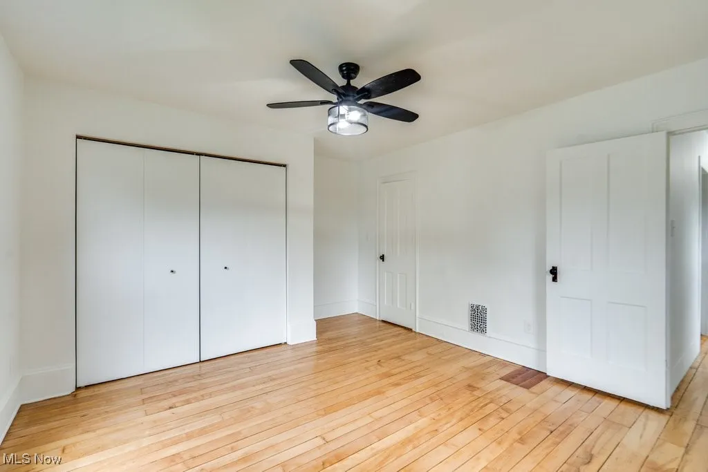 Unfurnished bedroom with light wood finished floors, a closet, and a ceiling fan