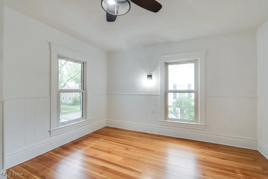 Spare room with wainscoting, light wood-style floors, and ceiling fan