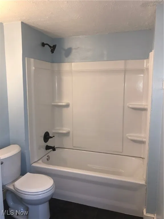 Bathroom featuring a textured ceiling and shower / tub combination