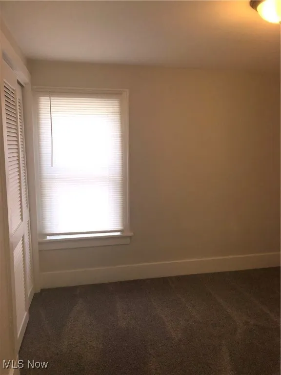 Unfurnished room with dark carpet and healthy amount of natural light