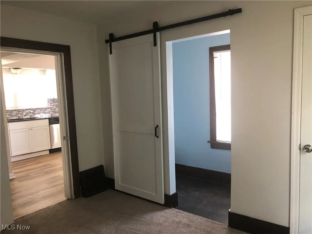 1st floor bedroom featuring a barn door and carpet flooring