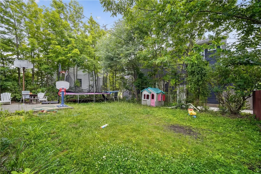 View of green lawn featuring a trampoline and a patio area