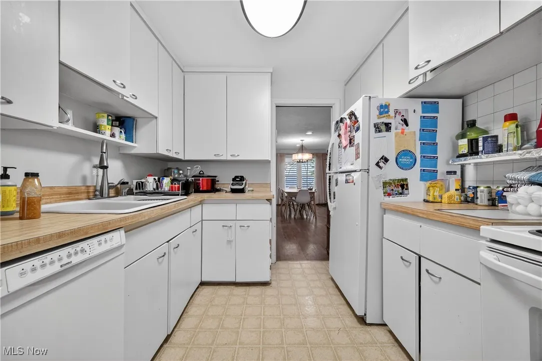 Kitchen with white appliances, light flooring, light countertops, and white cabinetry