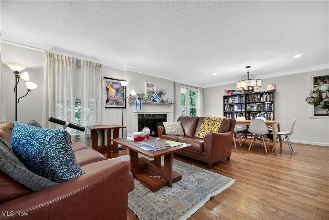 Living area featuring wood finished floors, a textured ceiling, a fireplace, and crown molding