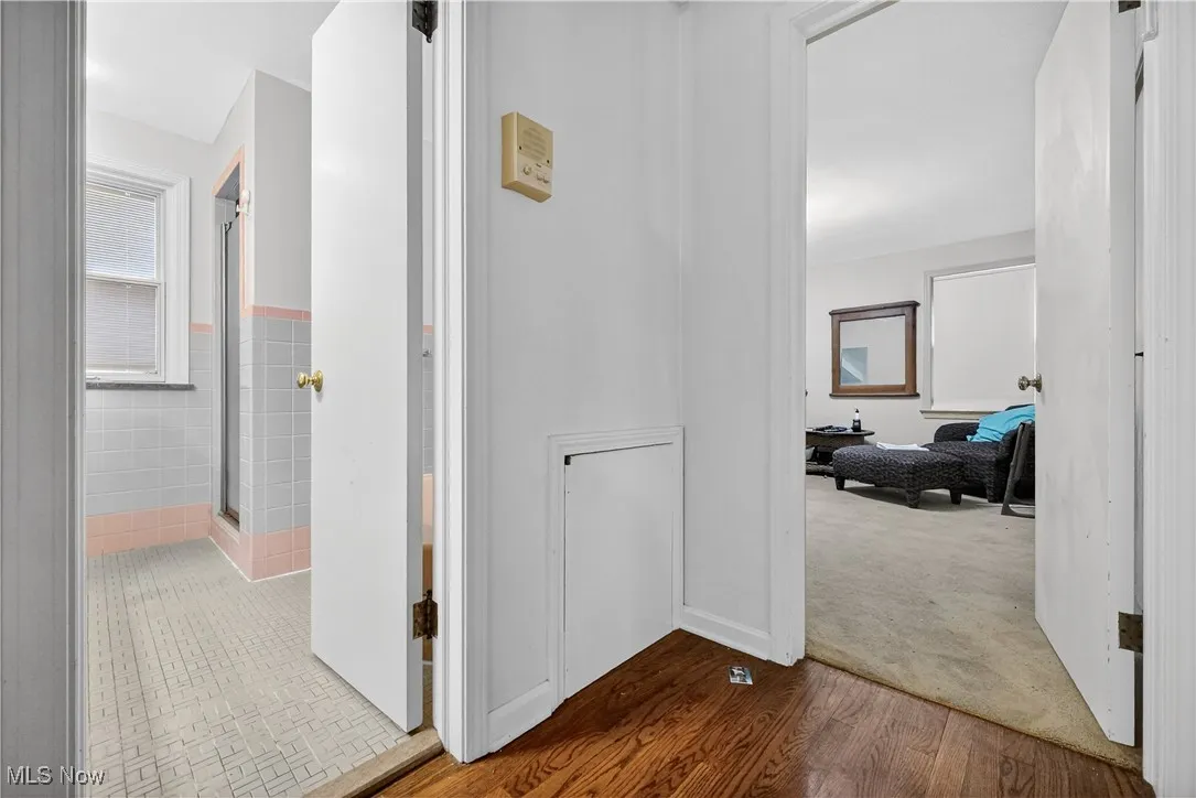 Hallway with wood finished floors, carpet floors, and tile walls