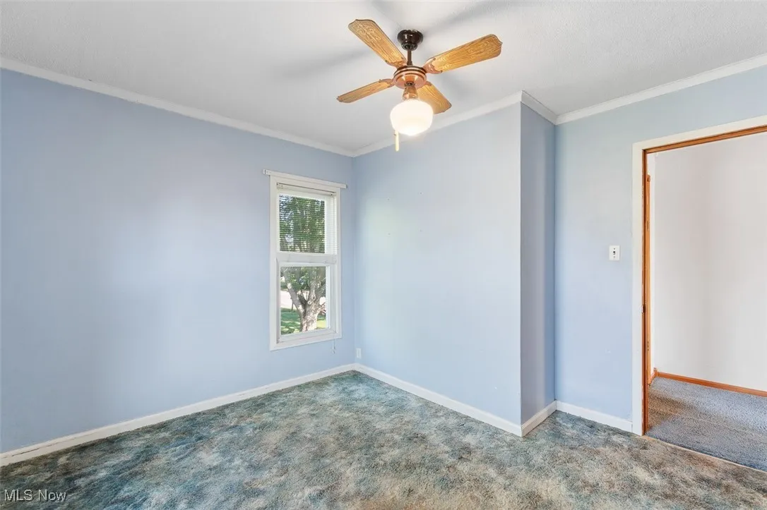 Carpeted bedroom featuring crown molding and ceiling fan