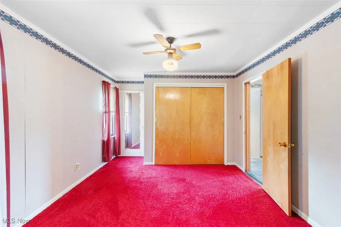 Bedroom featuring dark colored carpet, a ceiling fan, and a closet