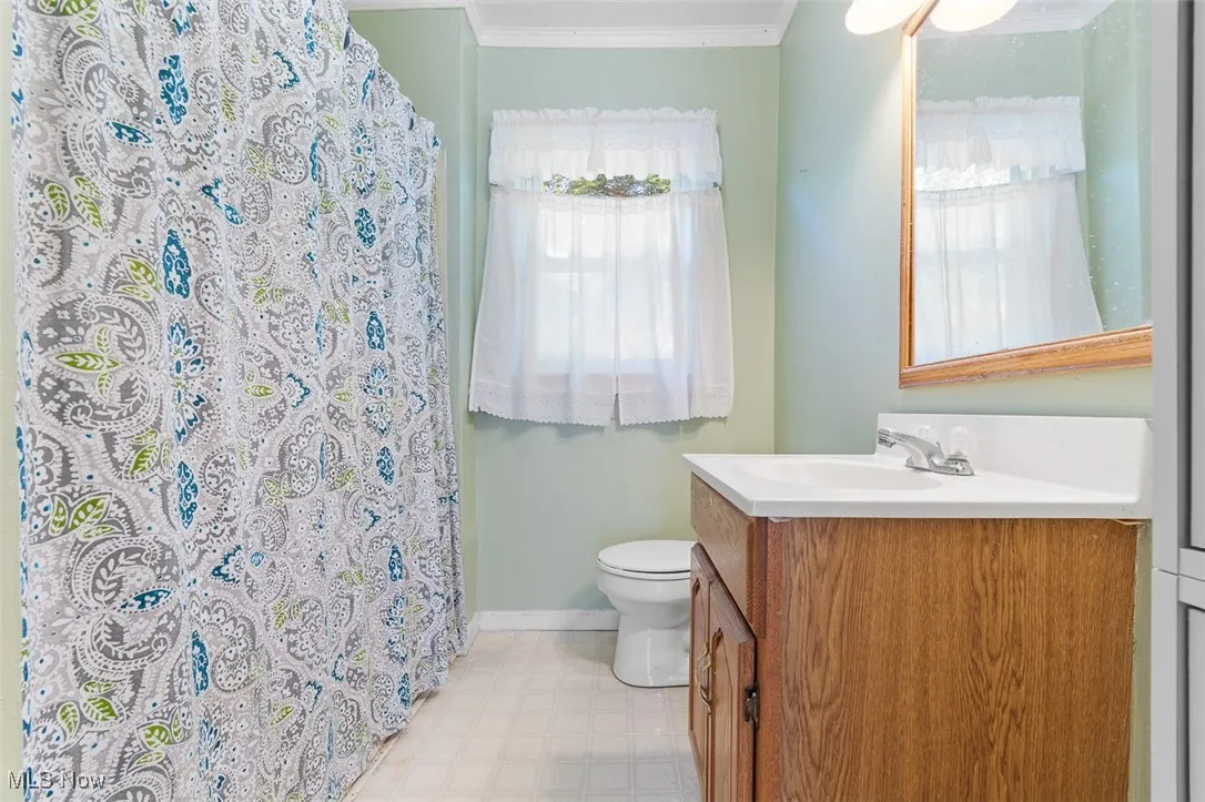 Full bathroom featuring vanity, tile patterned floors, crown molding, and curtained shower