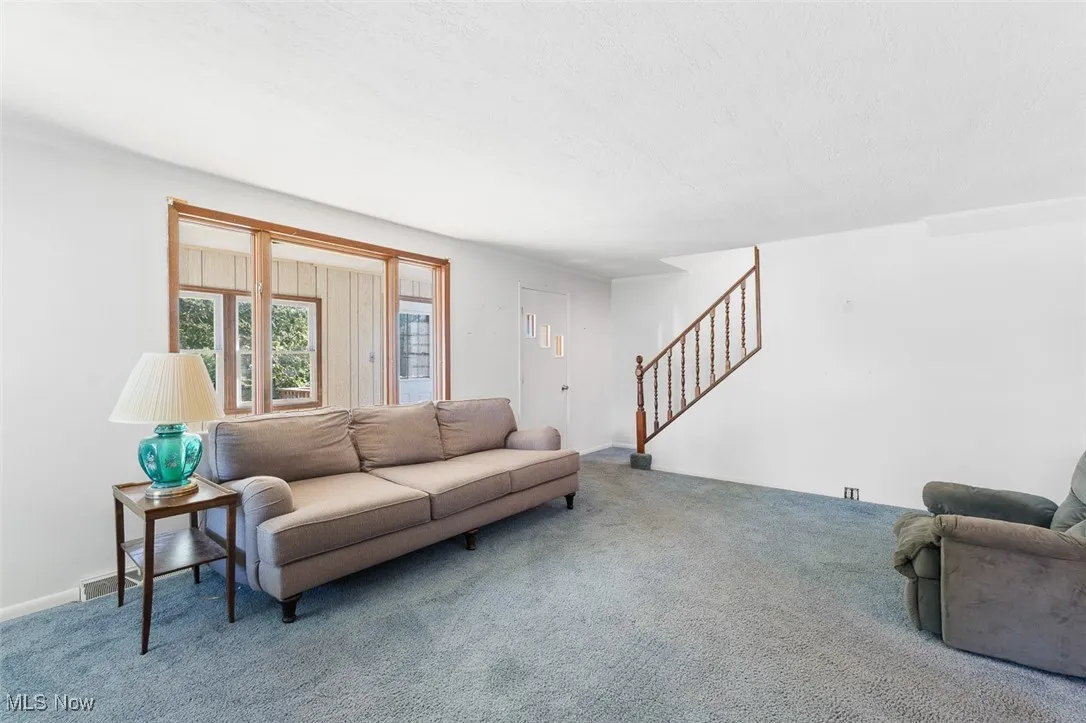 Carpeted living area with stairway