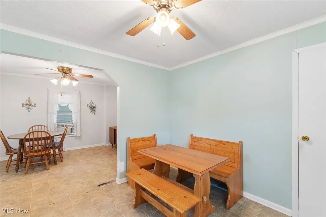 Dining area with a ceiling fan, crown molding, and arched walkways