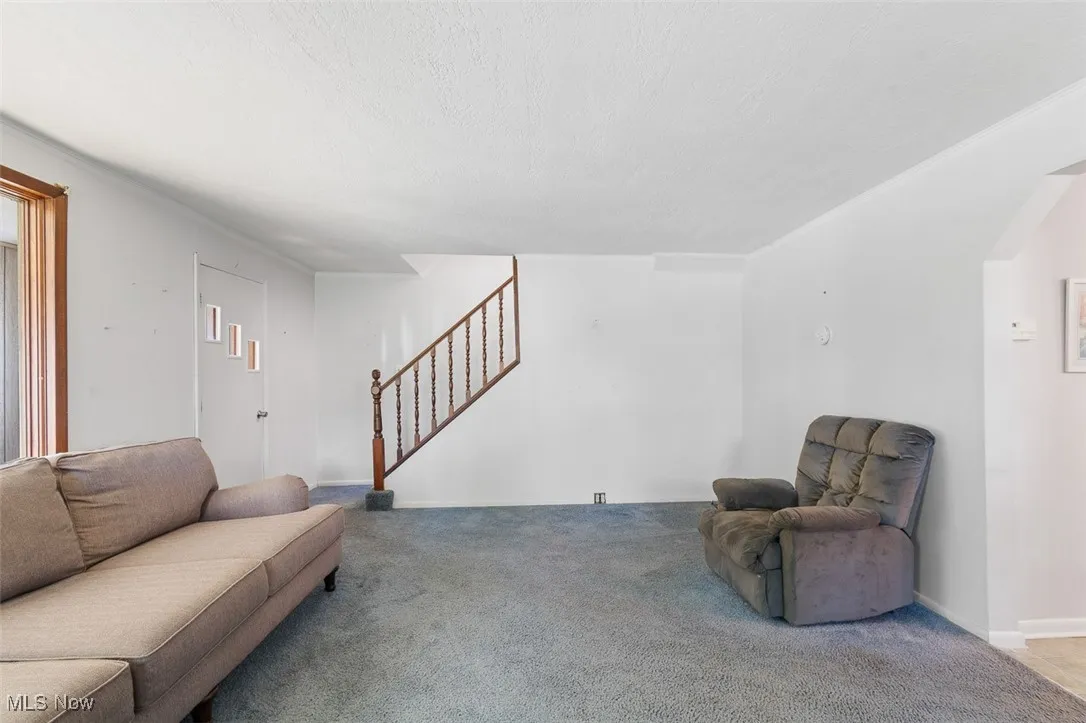 Living area with stairway, carpet floors, and a textured ceiling