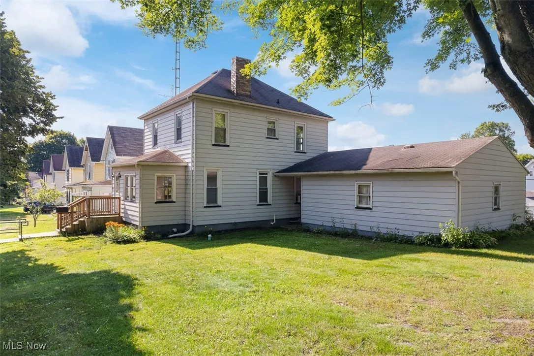 Front of house with a chimney, a yard, and a deck