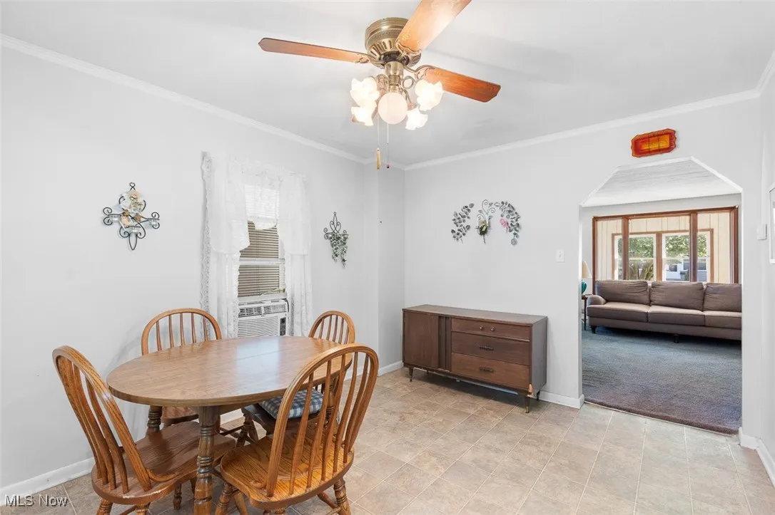 Dining area with a ceiling fan, cooling unit, ornamental molding, and arched walkways