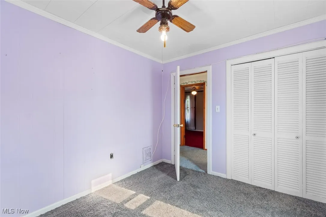 Bedroom with carpet floors, crown molding, a closet, and ceiling fan