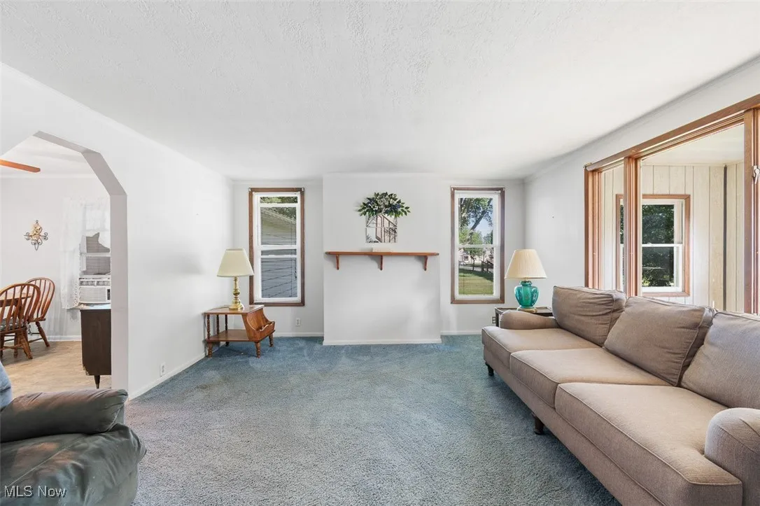 Carpeted living area with a textured ceiling and arched walkways