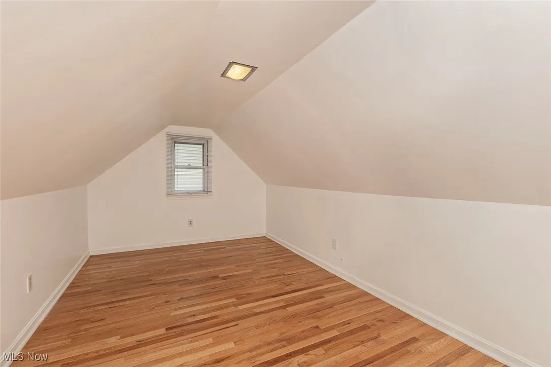 Bonus room with light wood-style flooring and lofted ceiling