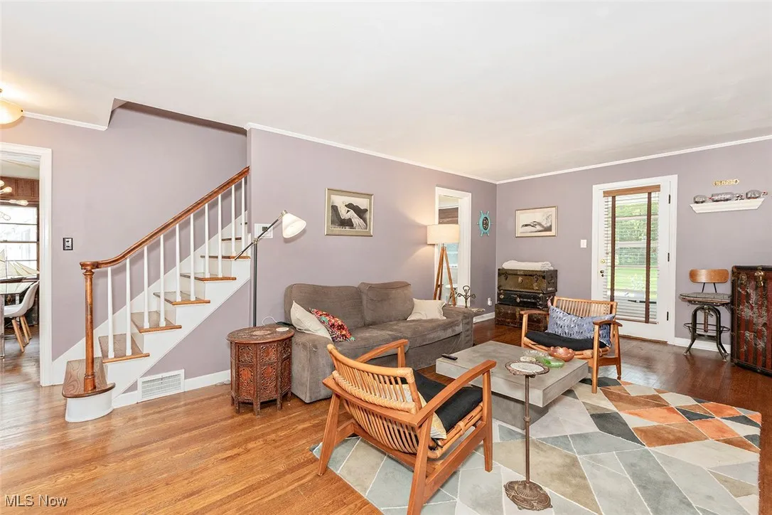 Living room featuring ornamental molding, stairs, and wood finished floors