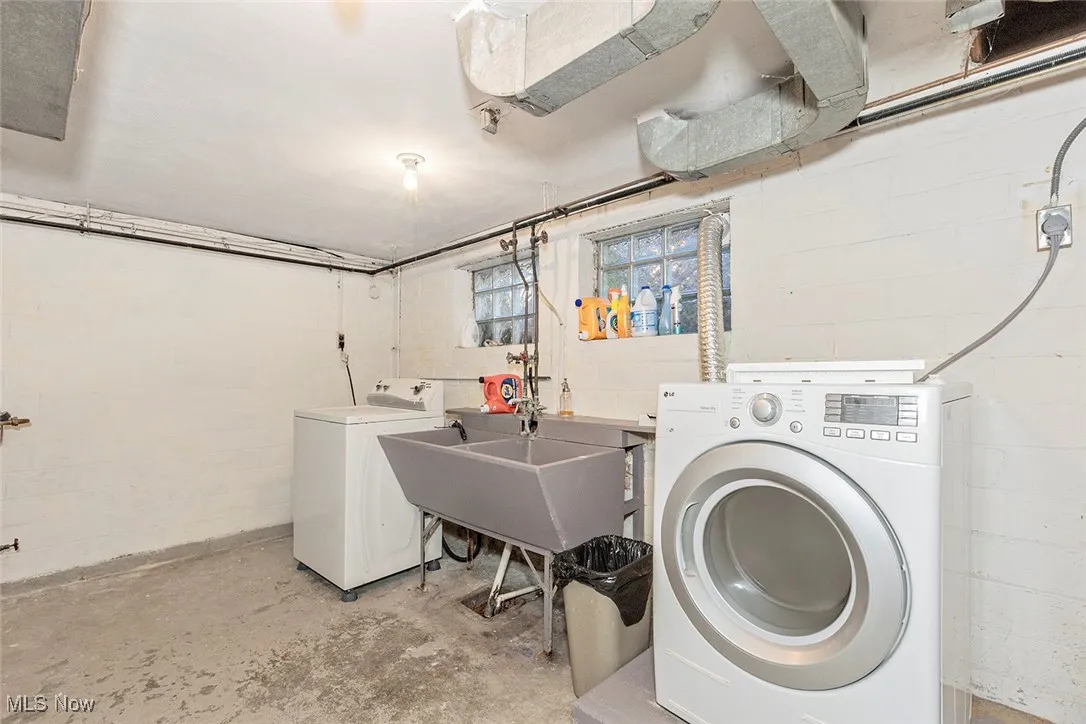 Washroom with washer and clothes dryer and concrete block wall
