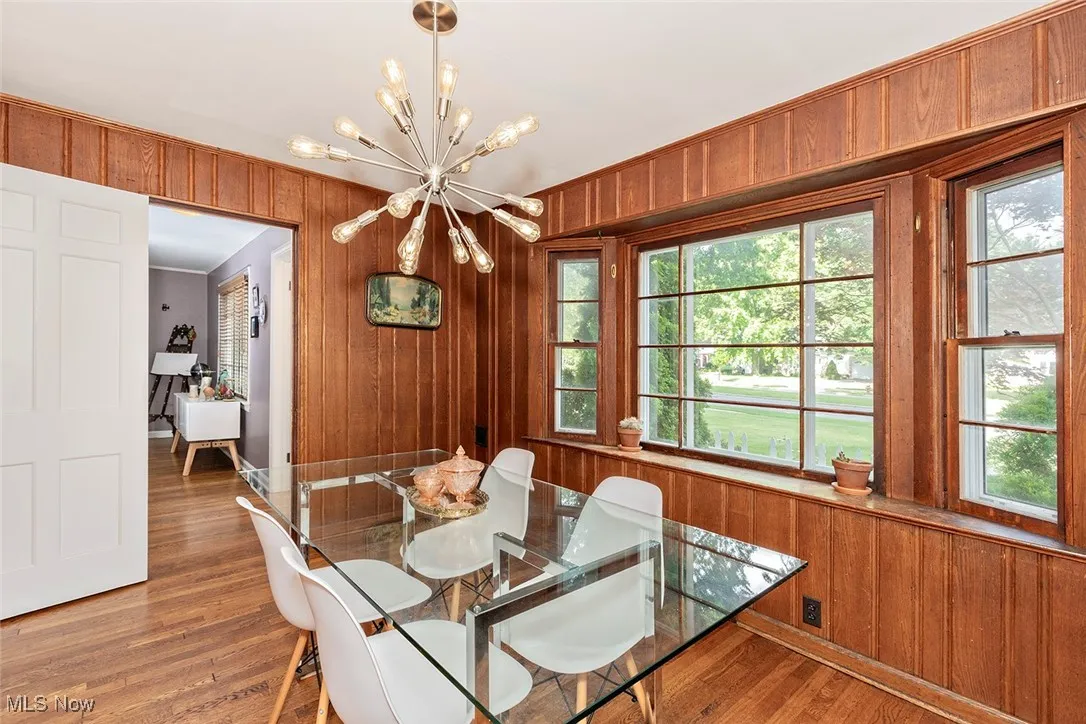 Dining space with a chandelier, wooden walls, and wood finished floors