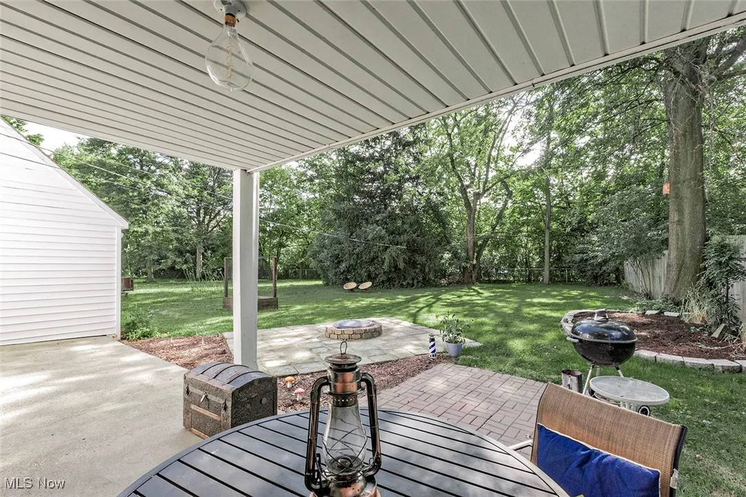 Wooden terrace with an outdoor fire pit, a patio, view of scattered trees, and outdoor dining space