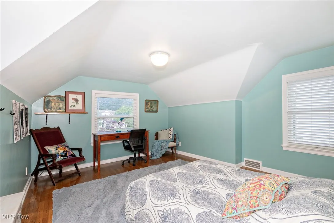 Bedroom with wood finished floors and lofted ceiling