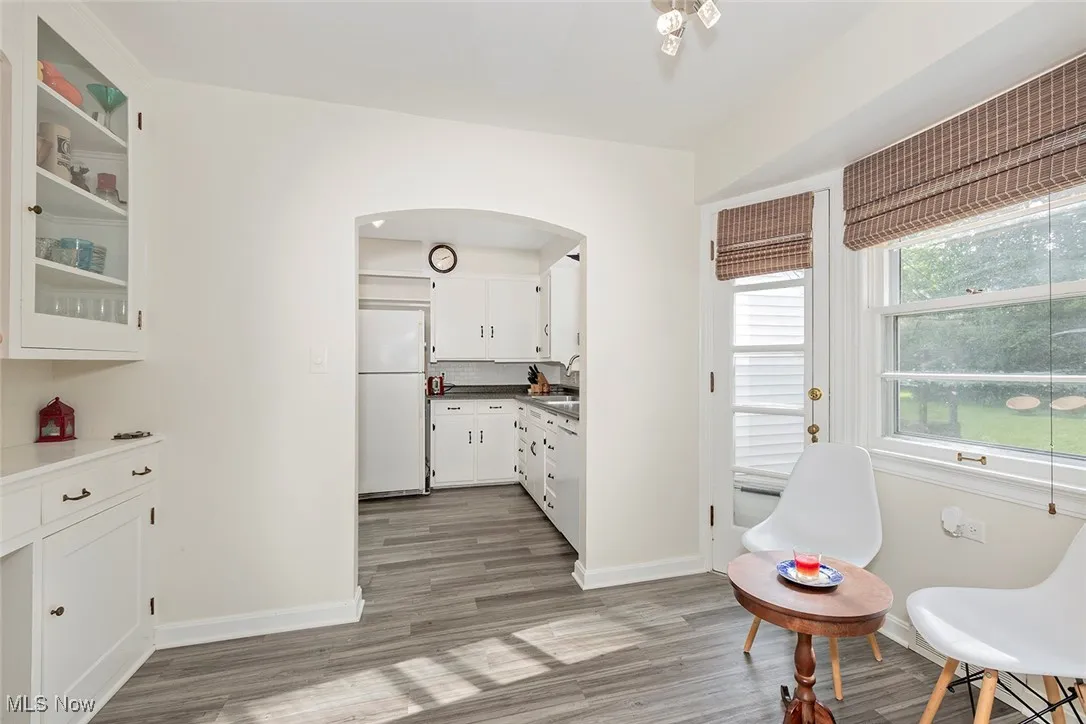 Kitchen featuring freestanding refrigerator, white cabinets, light wood-style flooring, and glass insert cabinets