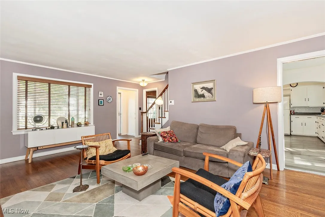 Living area featuring stairs, light wood-type flooring, and crown molding