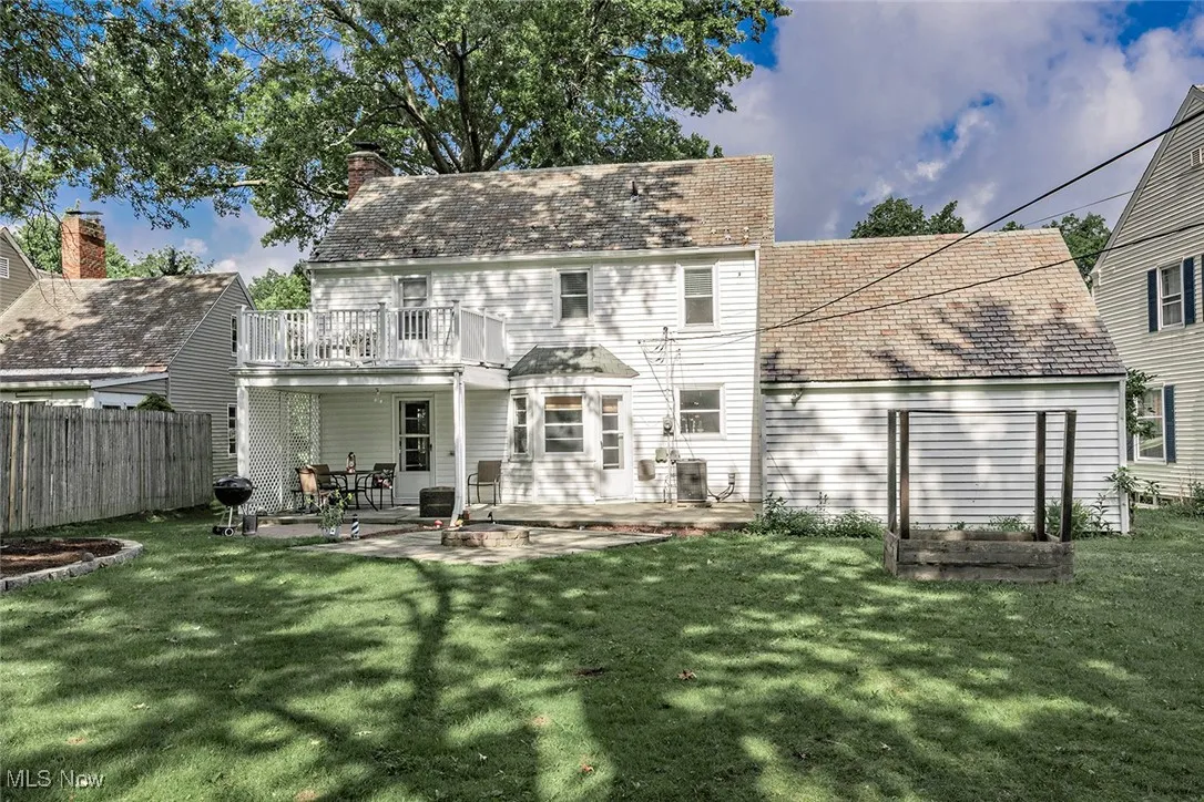 Rear view of house with a patio, a balcony, and a chimney