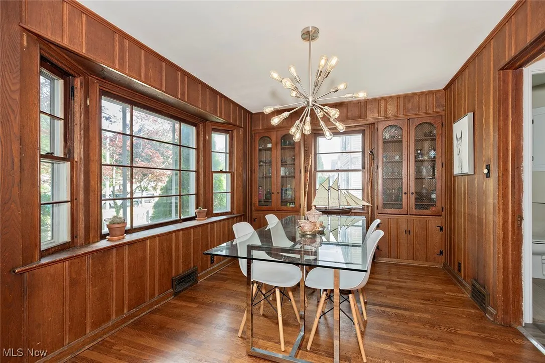 Dining space featuring wood walls, a chandelier, plenty of natural light, and dark wood-type flooring