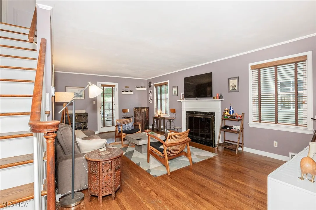 Living area featuring stairs, wood finished floors, a premium fireplace, and ornamental molding