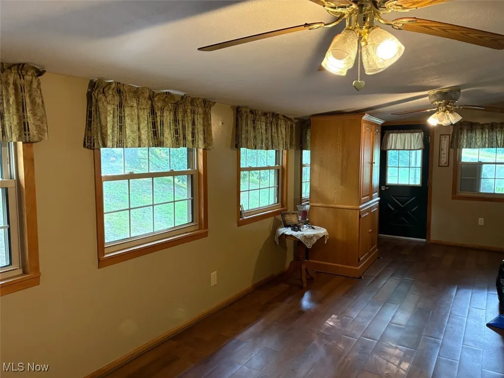 Living room featuring ceiling fan and dark wood-style flooring