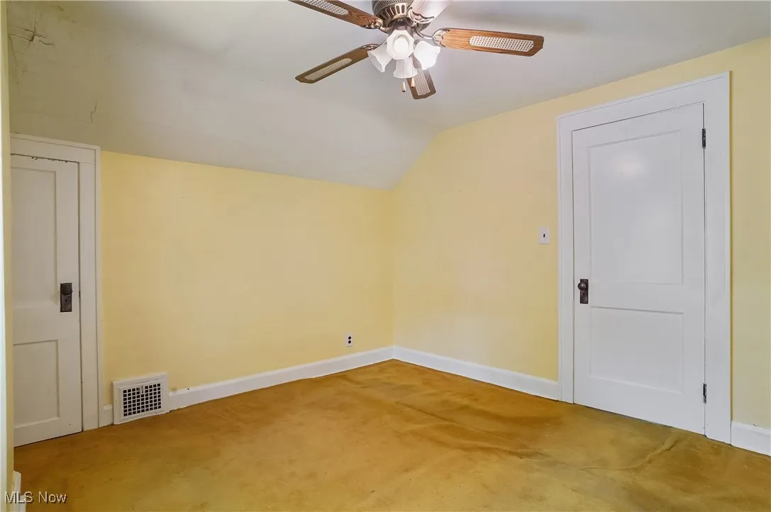 Bonus room featuring light carpet, lofted ceiling, and ceiling fan